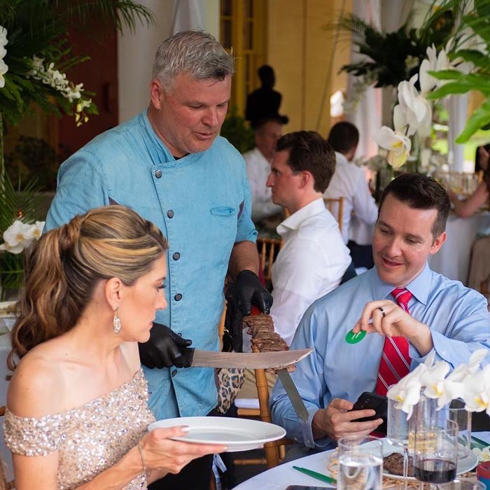 man serving meat skewers to guests